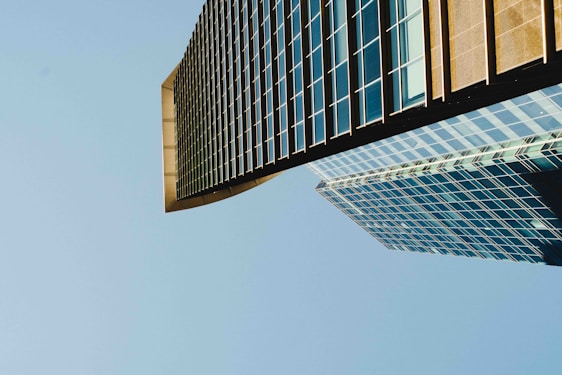 A sunlit modern skyscraper with glass facades reflecting a clear blue sky, symbolizing strength and elegance.