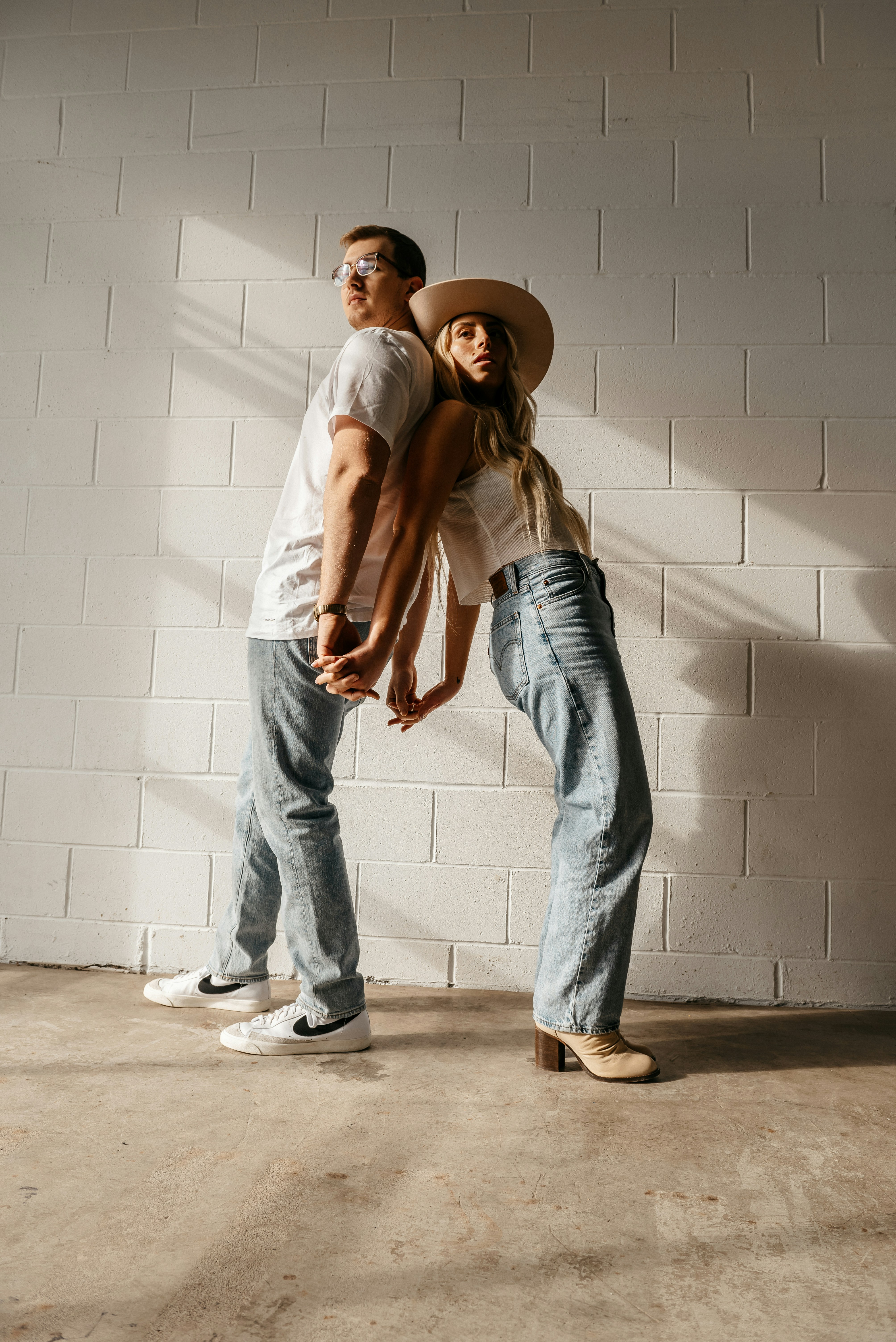 A man and a woman standing in front of a brick wall photo – Free ...