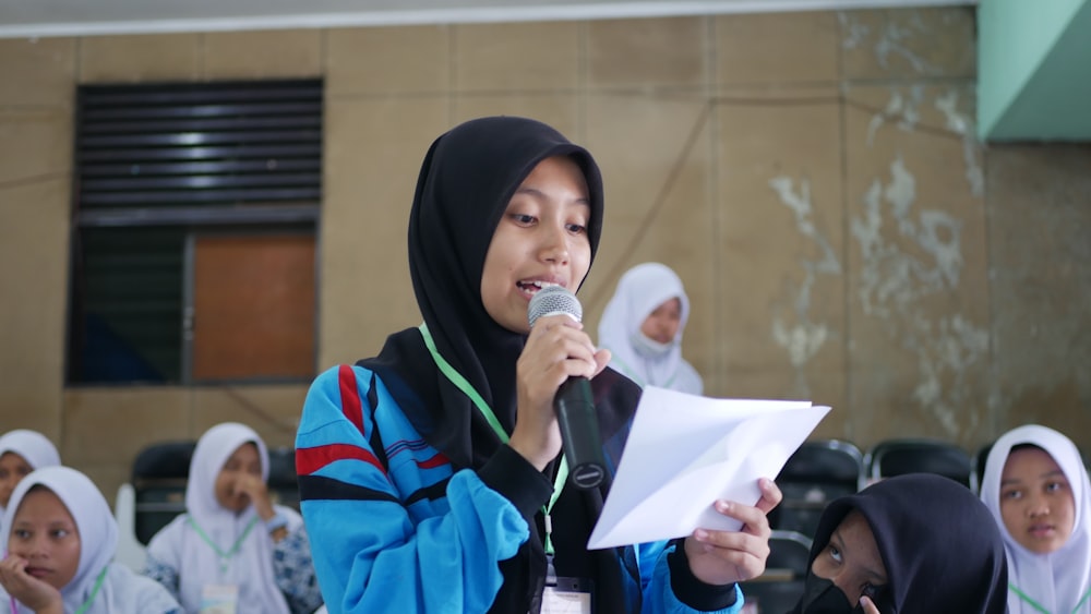 a woman holding a microphone in front of a group of people