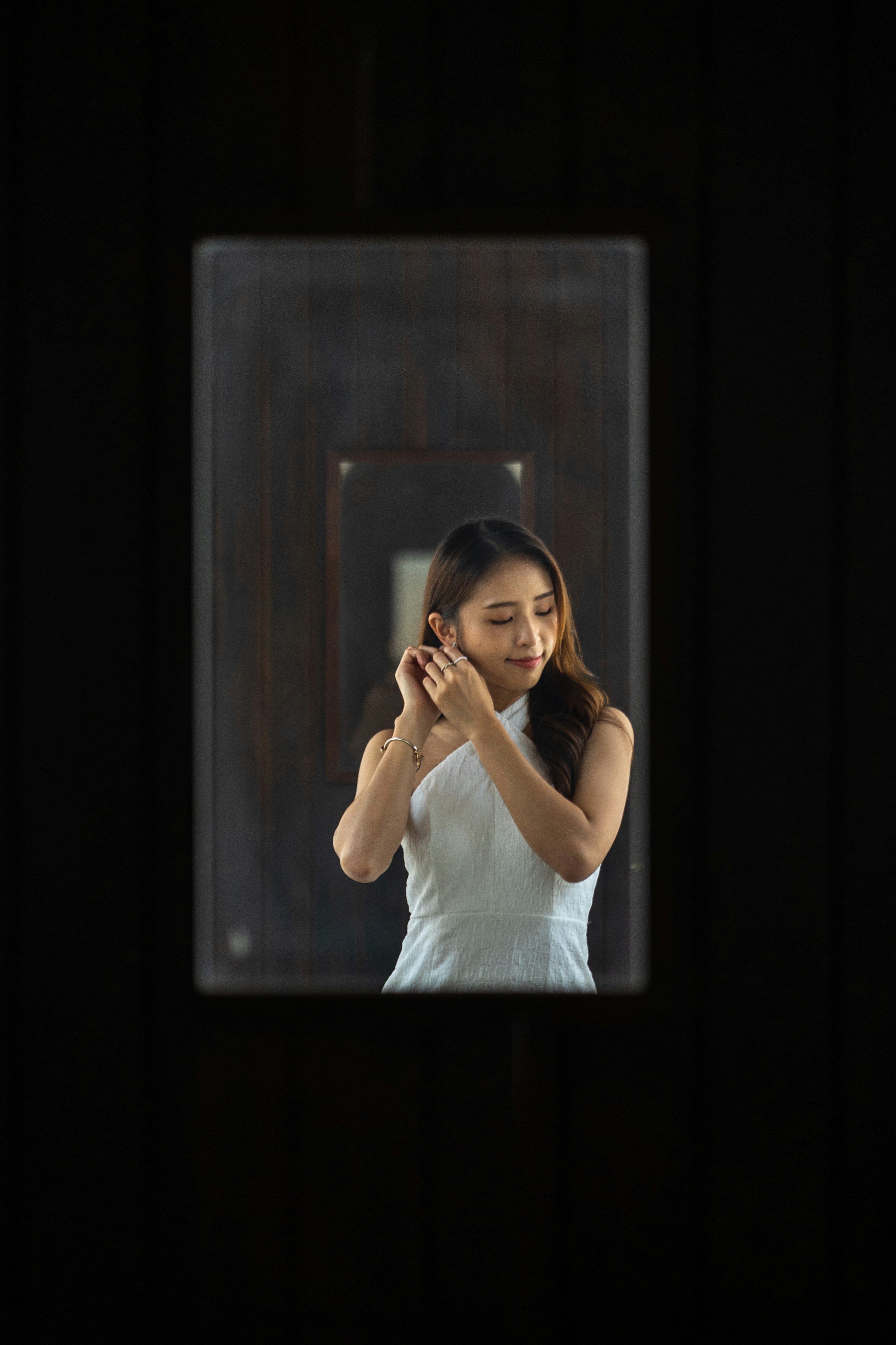 a woman standing in front of a mirror holding her hands together