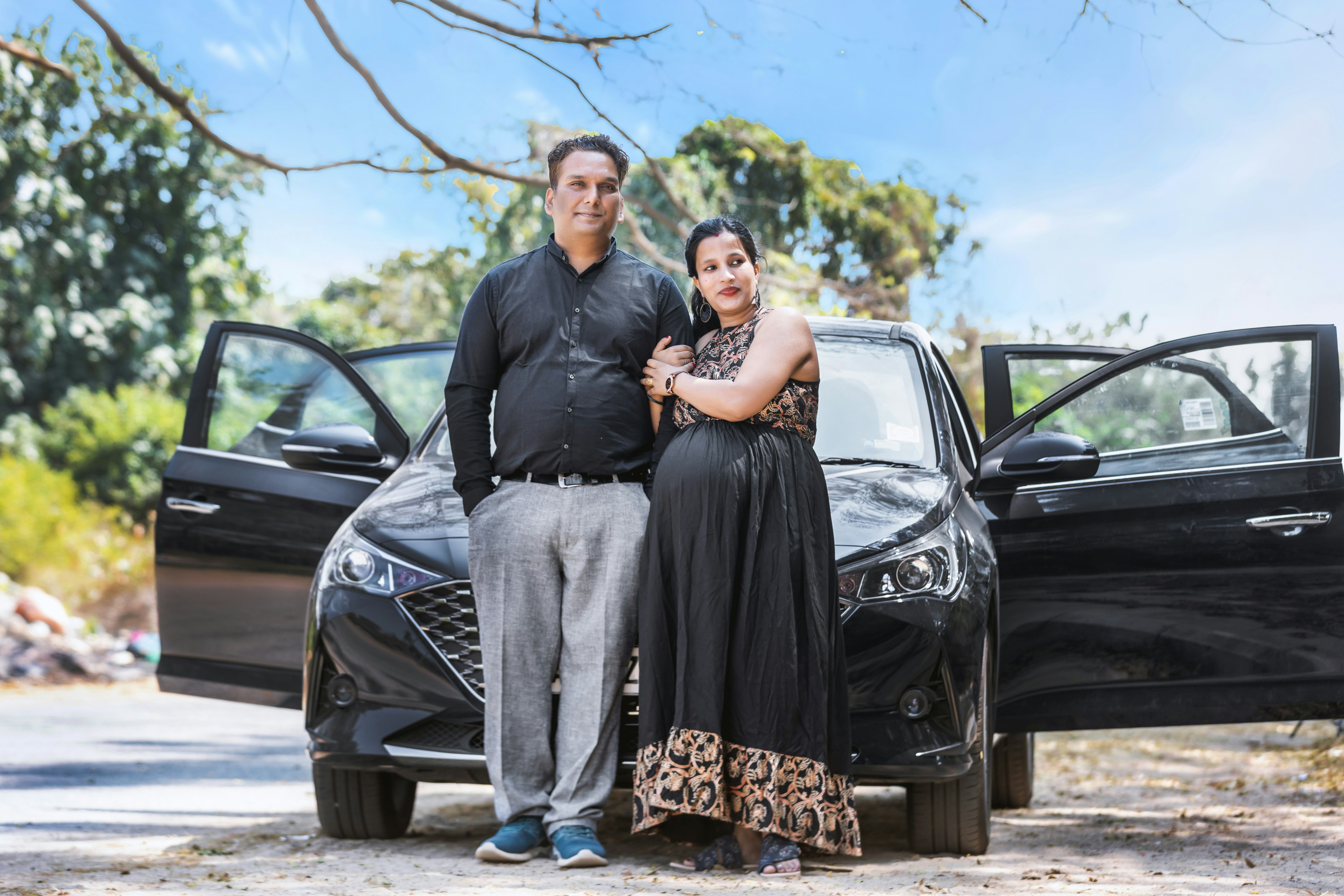 Couple comparing small used cars on a dealership lot