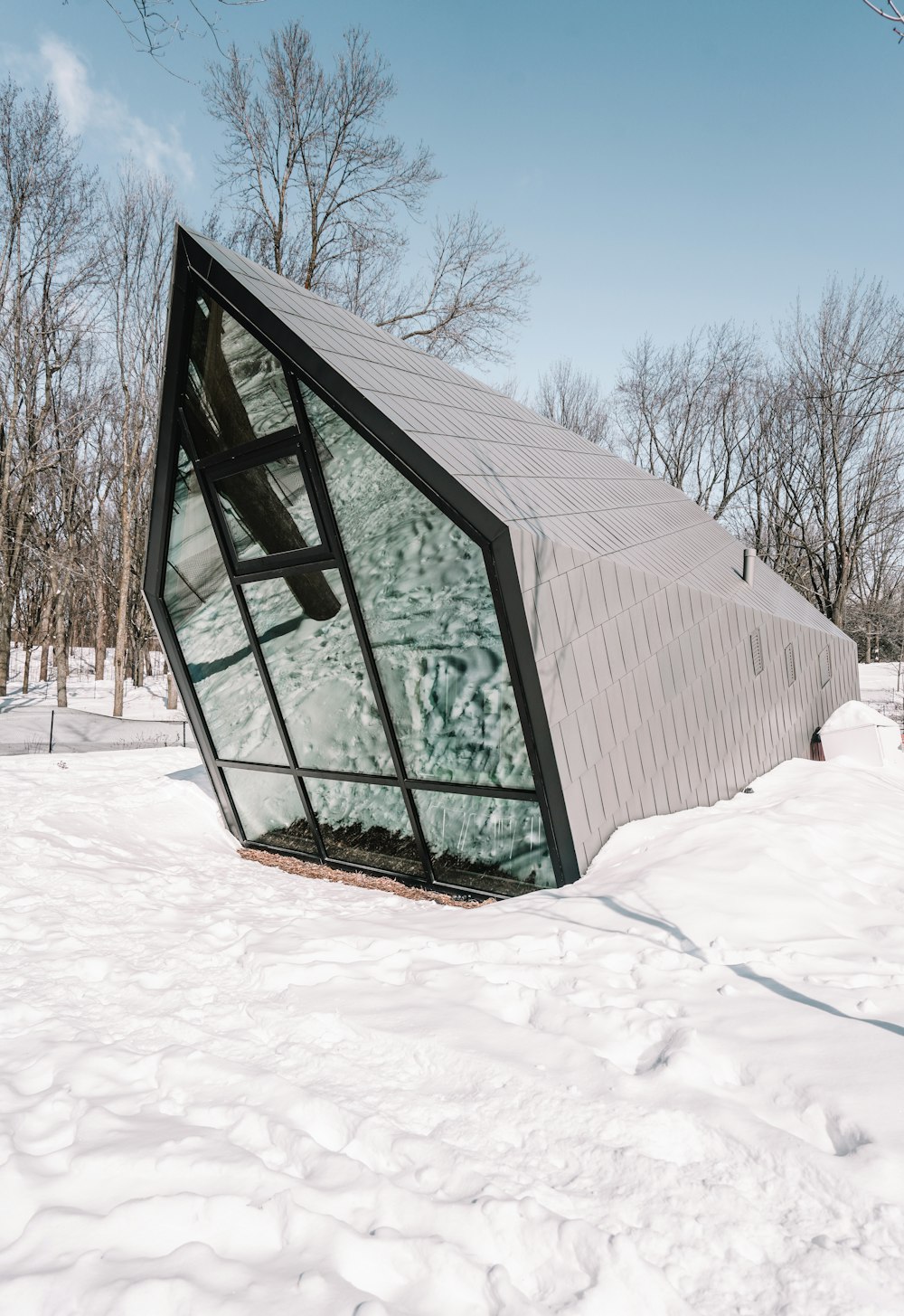 a triangular shaped building in the middle of a snow covered field