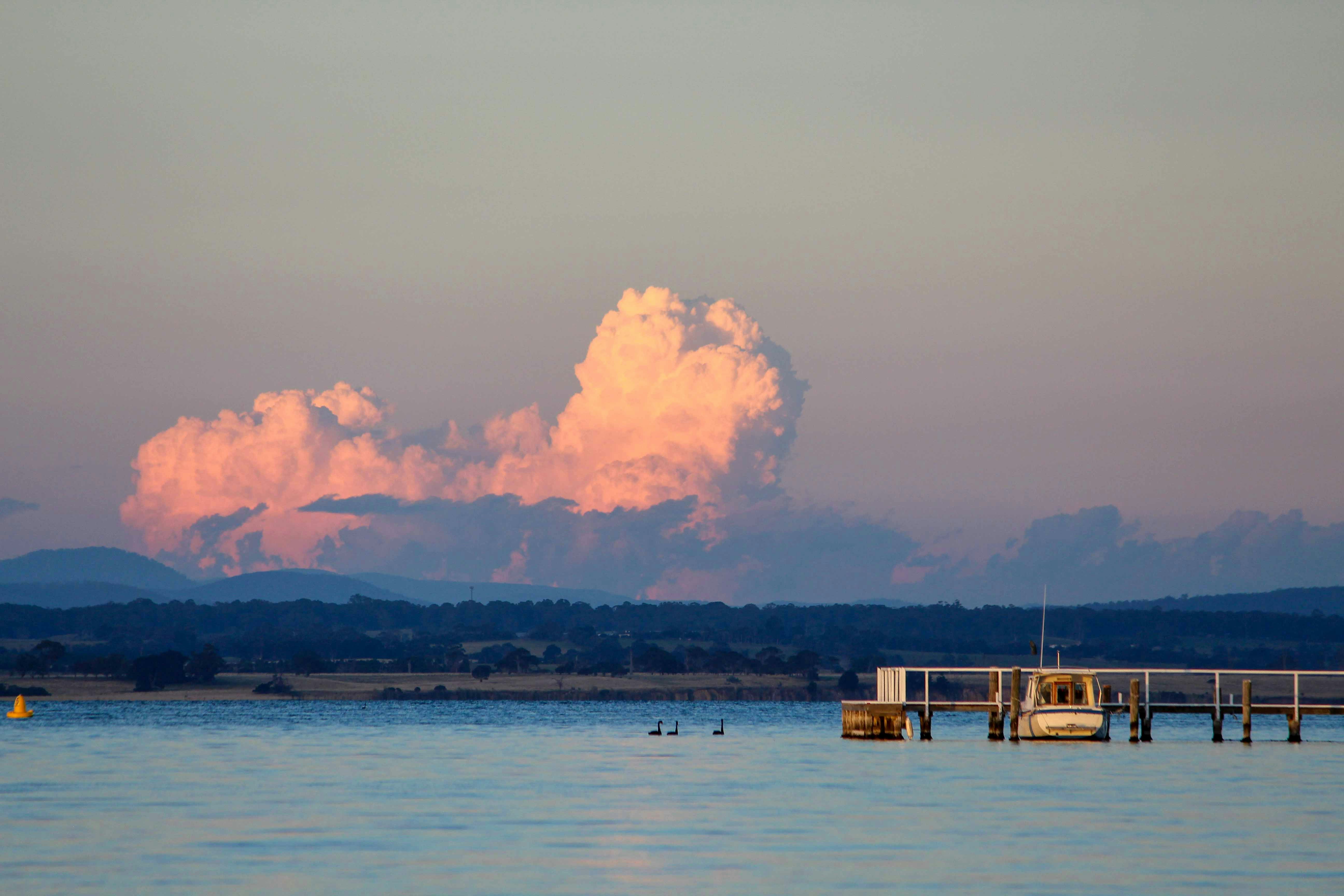a large cloud hangs over a body of water