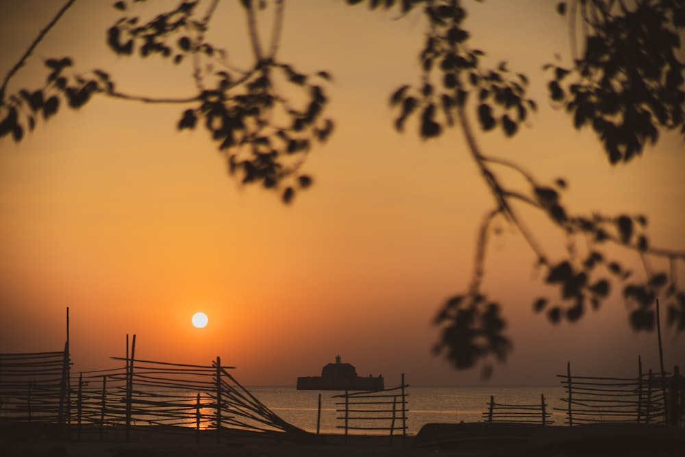 the sun is setting over the ocean with a boat in the distance