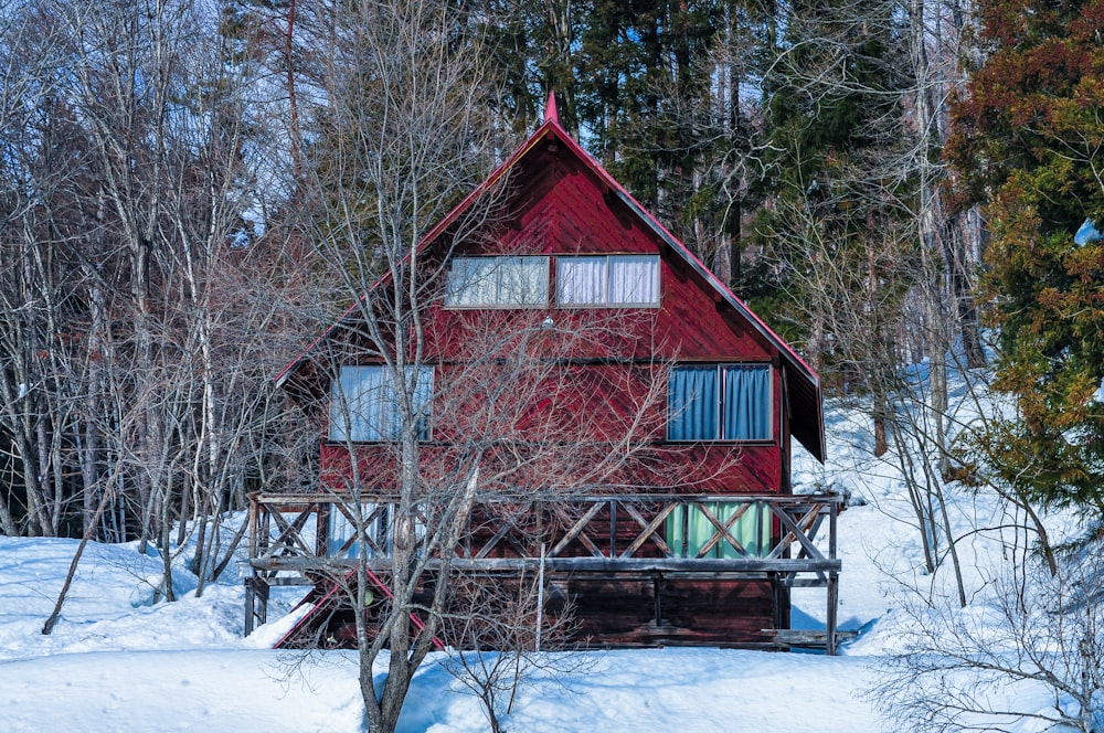 a red house in the middle of a snowy forest