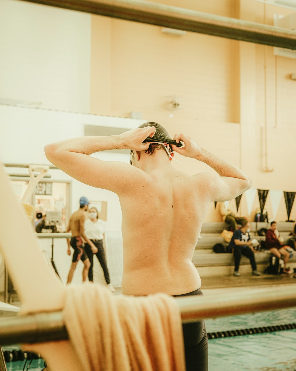 a man with no shirt standing next to a swimming pool