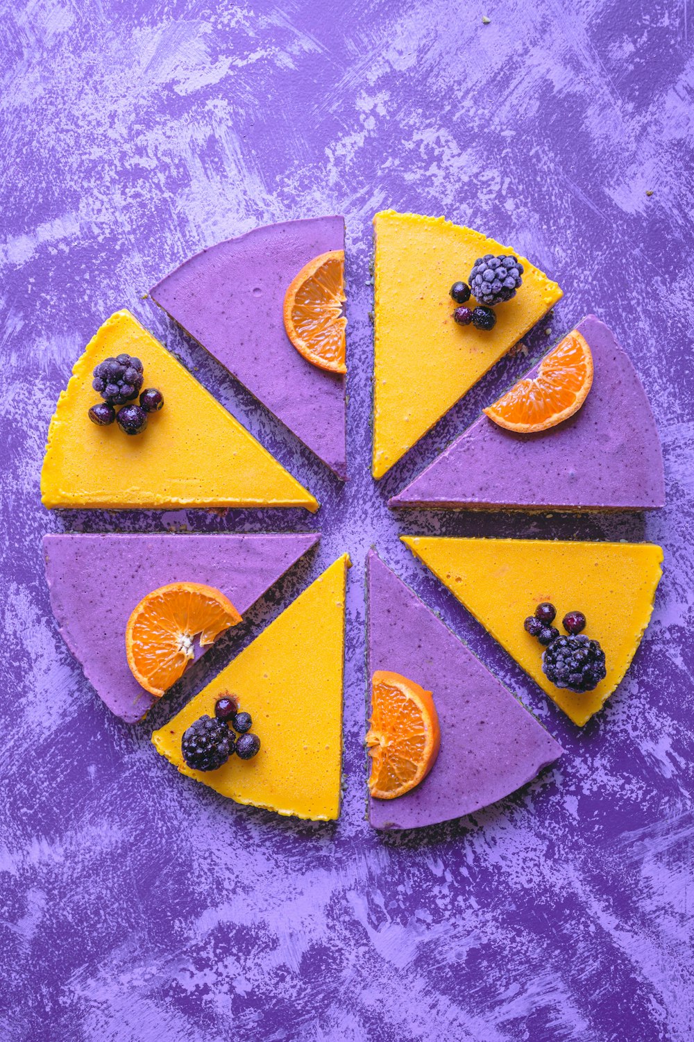 a purple and yellow cake with fruit on it