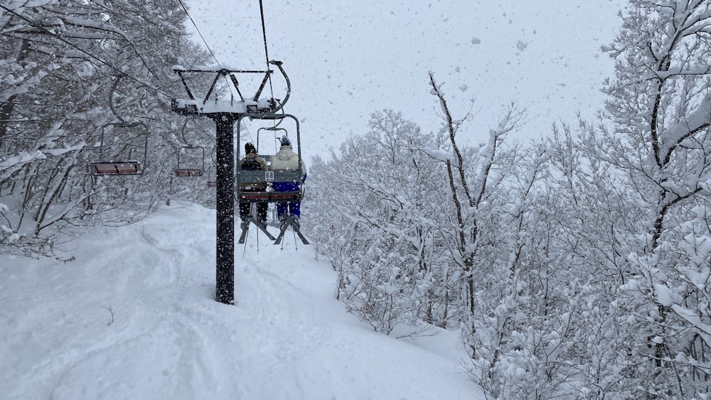 two people riding a ski lift in the snow