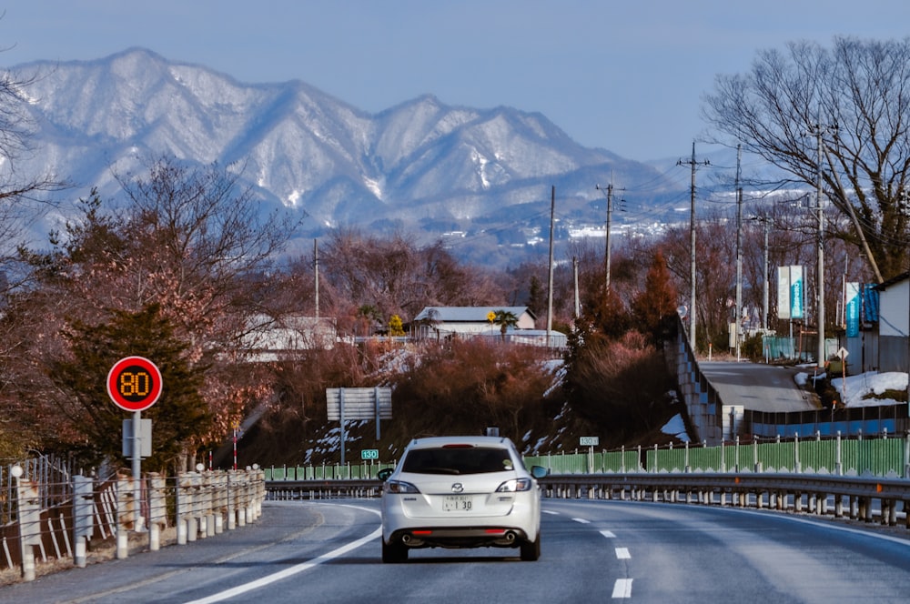 a car driving down a road with mountains in the background