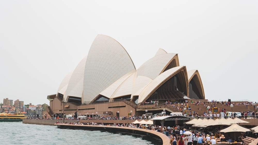 a crowd of people standing around a building next to a body of water