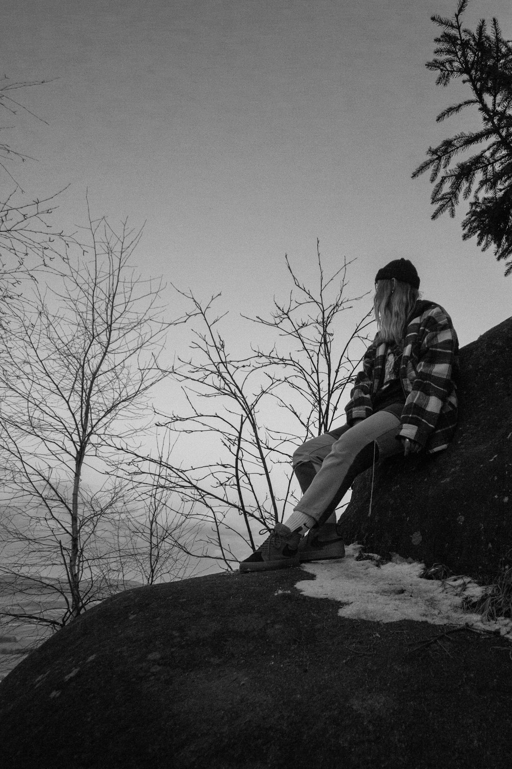 a man sitting on top of a rock next to a tree