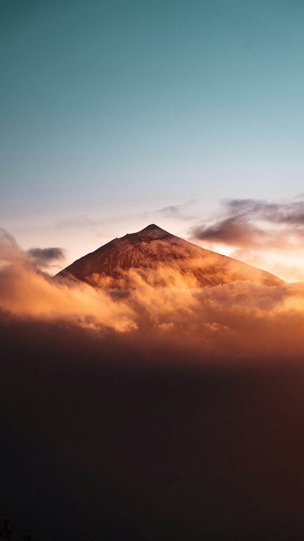 a mountain covered in clouds at sunset