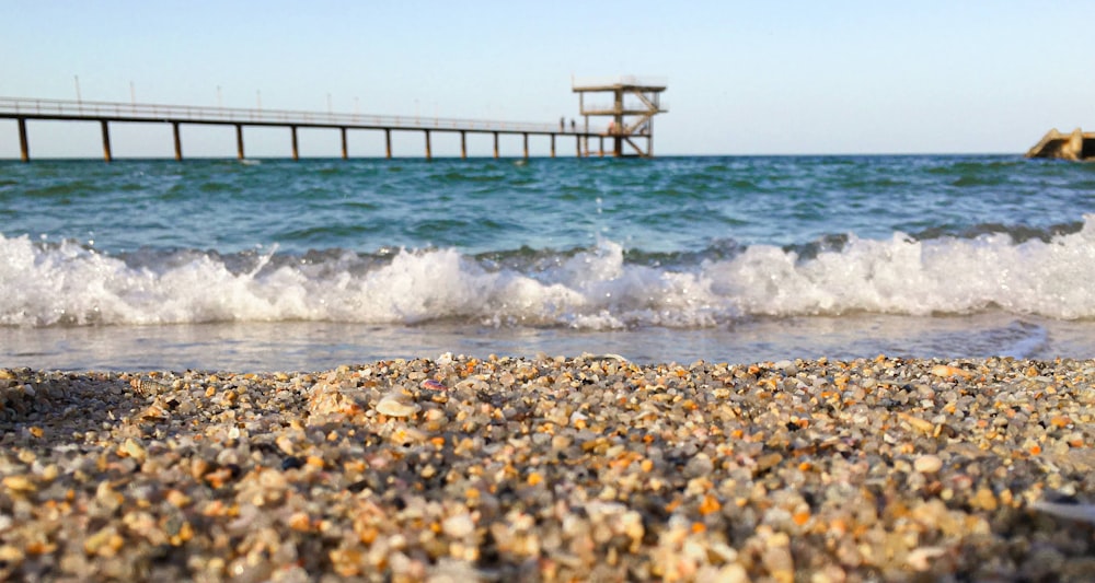 a close up of a beach with a pier in the background