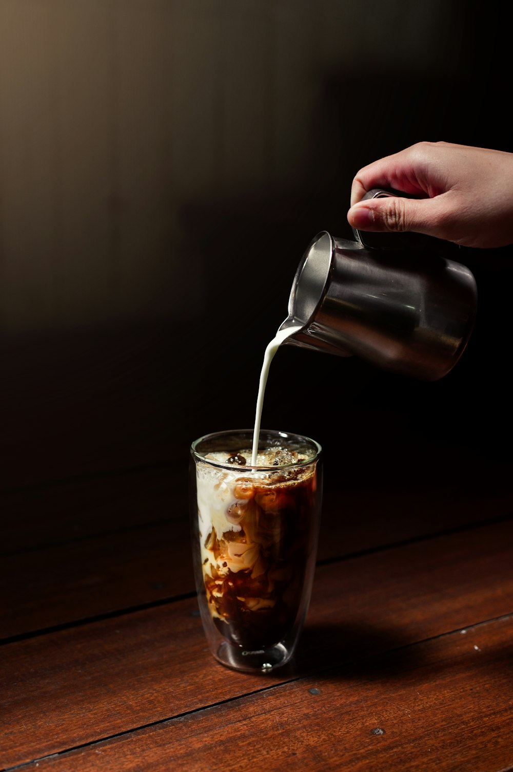 a person pouring something into a glass on a table