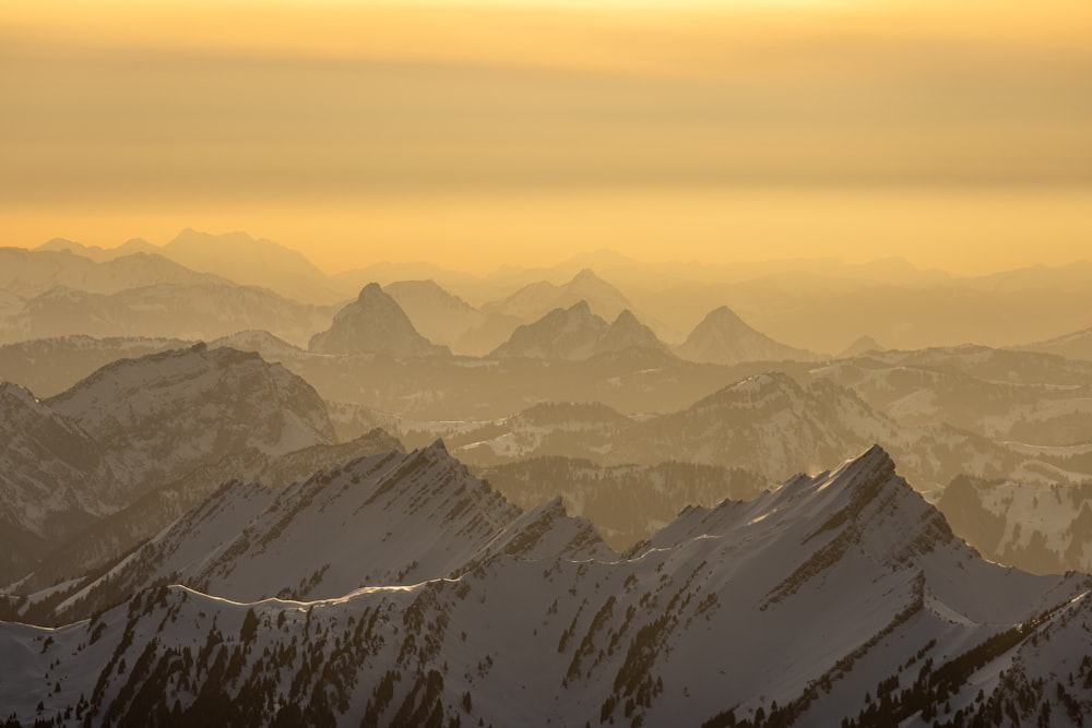 a group of mountains covered in snow under a cloudy sky