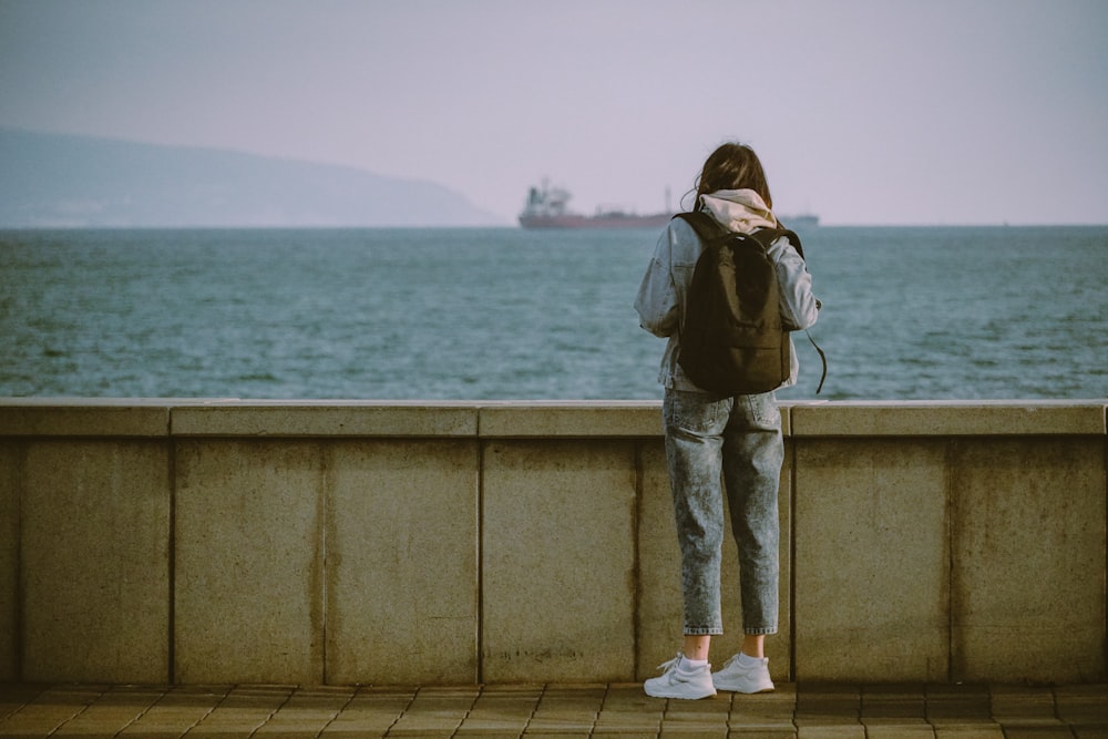 a person with a backpack looking out over the water