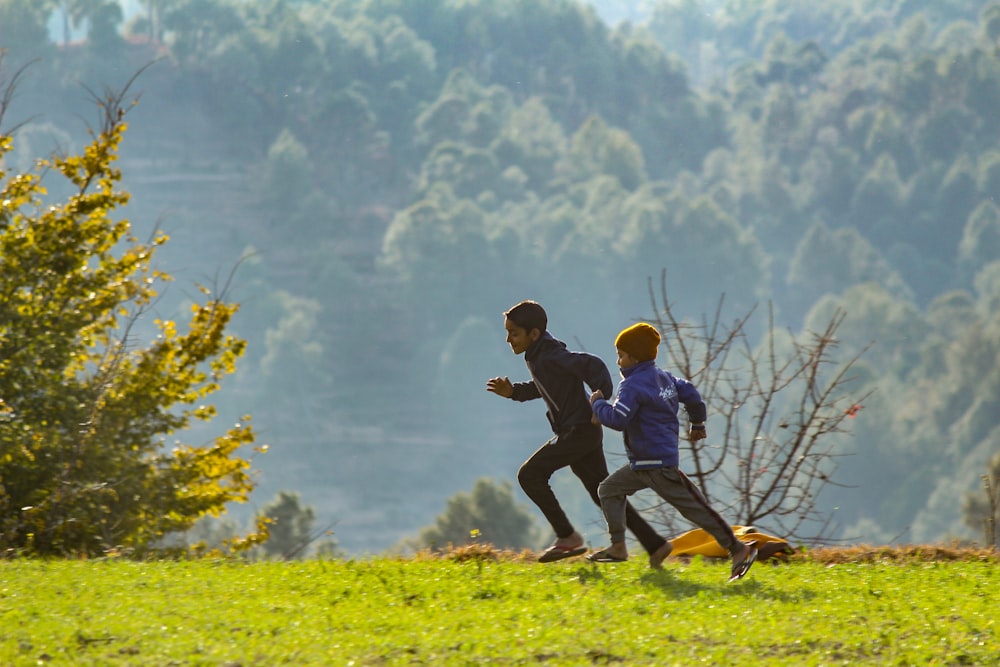 a couple of men running across a lush green field