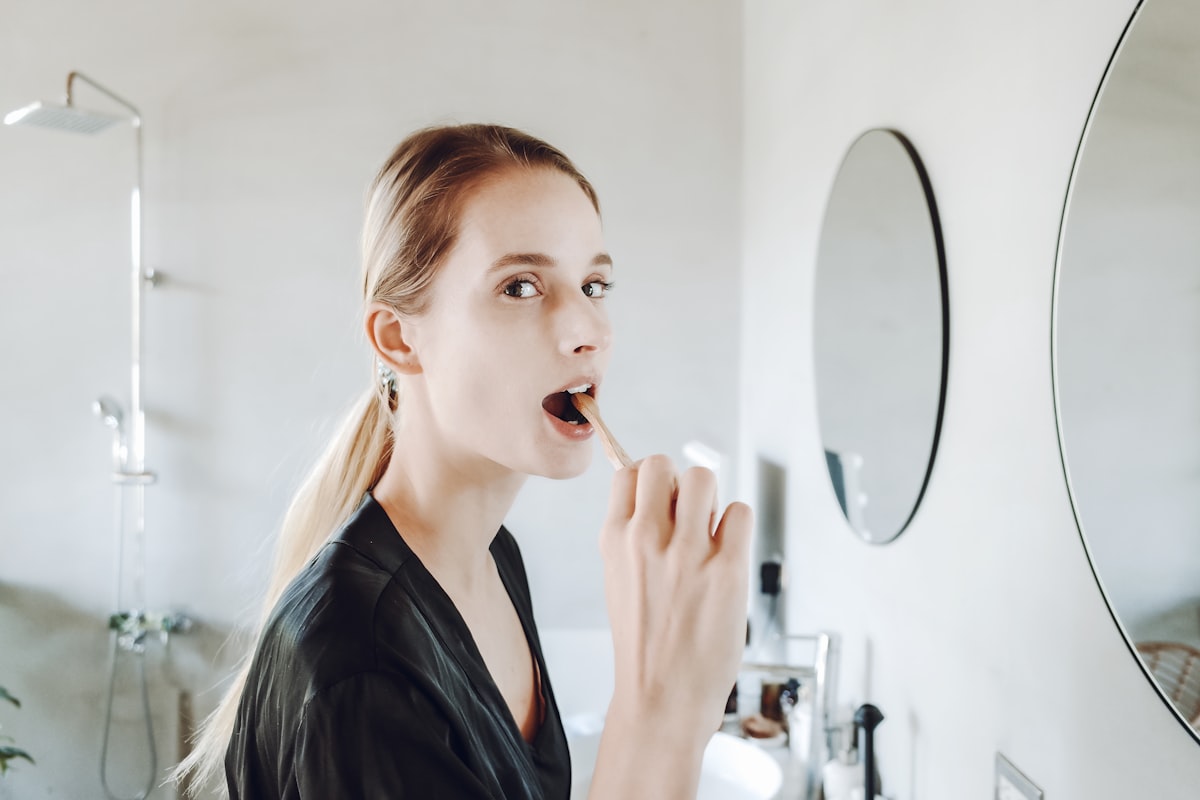 Woman brushing her teeth in front of a mirror as part of a daily oral hygiene routine