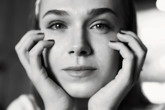 a black and white photo of a woman holding her hands to her face