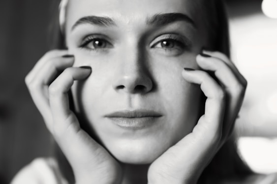 a black and white photo of a woman holding her hands to her face