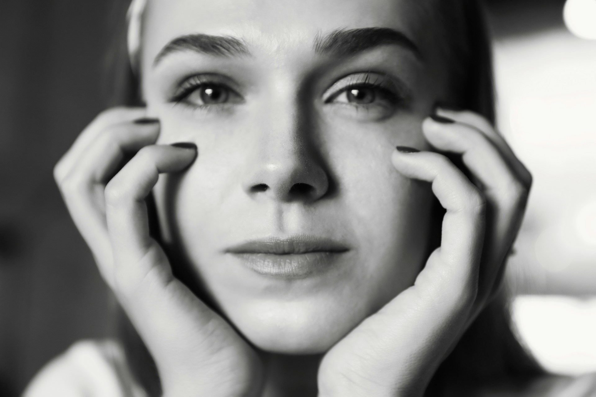 A serene black and white portrait capturing the quiet intensity of a thoughtful subject against a blurred urban backdrop.