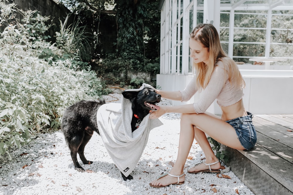 a woman sitting on a bench petting a dog