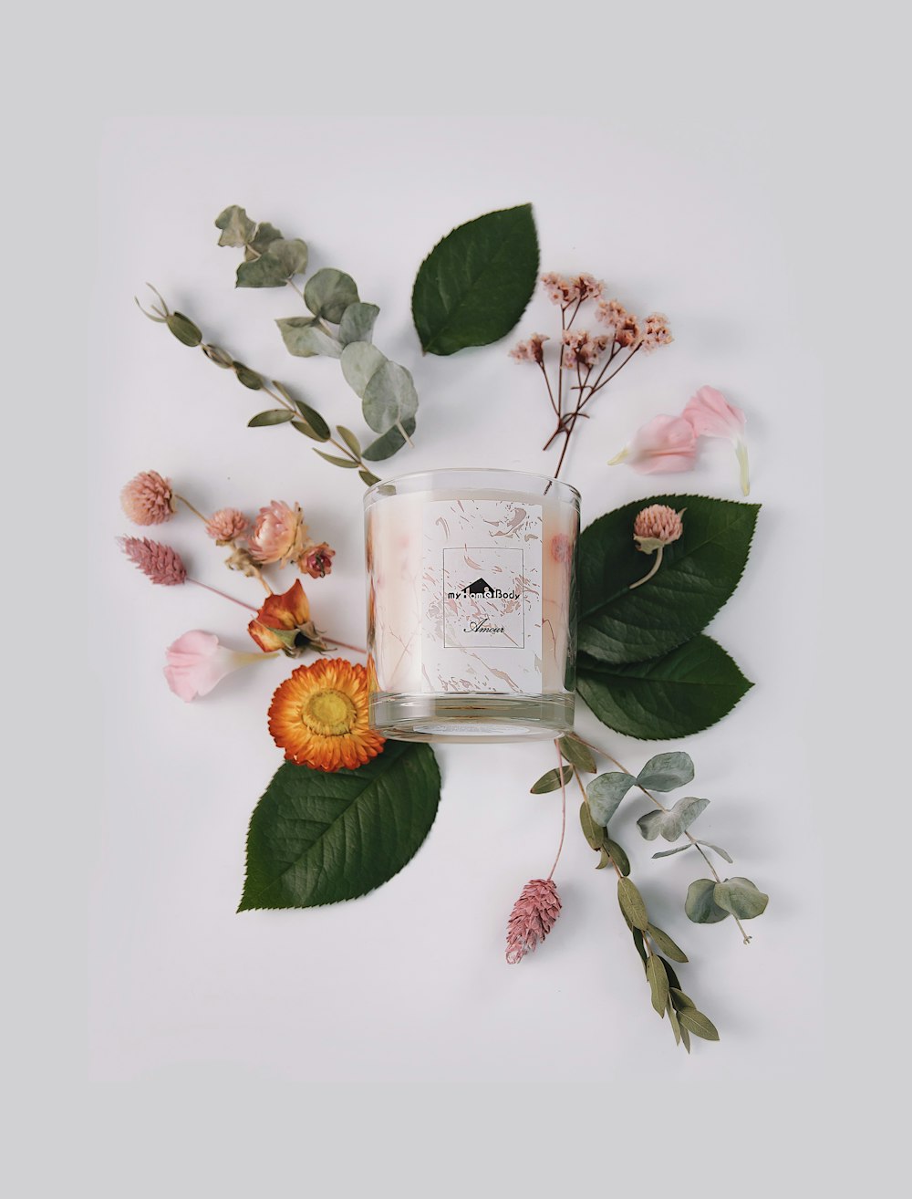 a candle surrounded by flowers and leaves