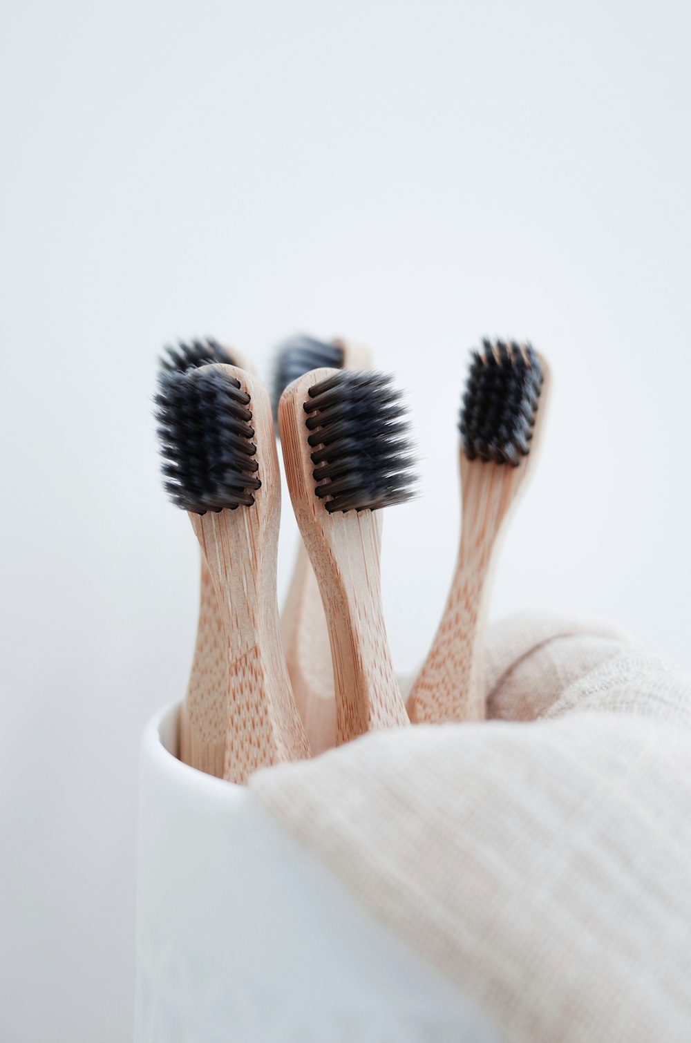 three wooden toothbrushes in a white cup