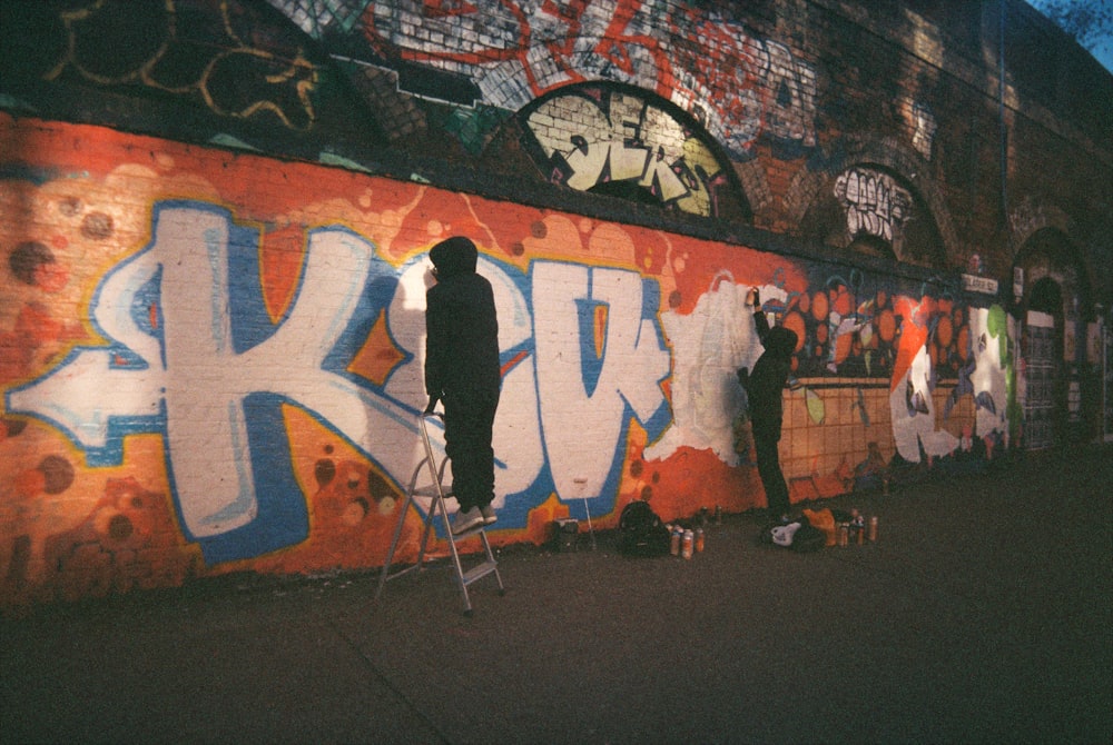 two men are painting graffiti on a wall