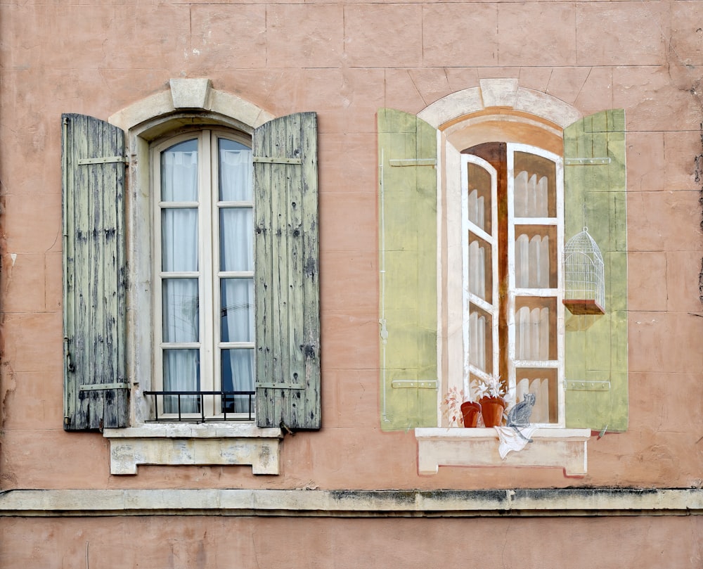 two windows with green shutters on a building