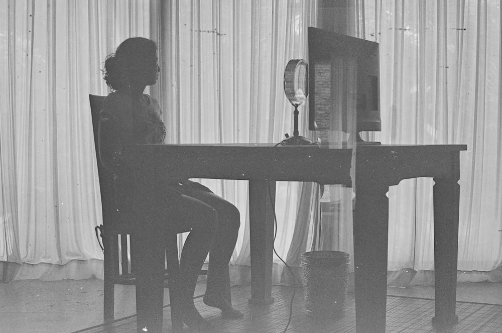 a black and white photo of a woman sitting at a desk