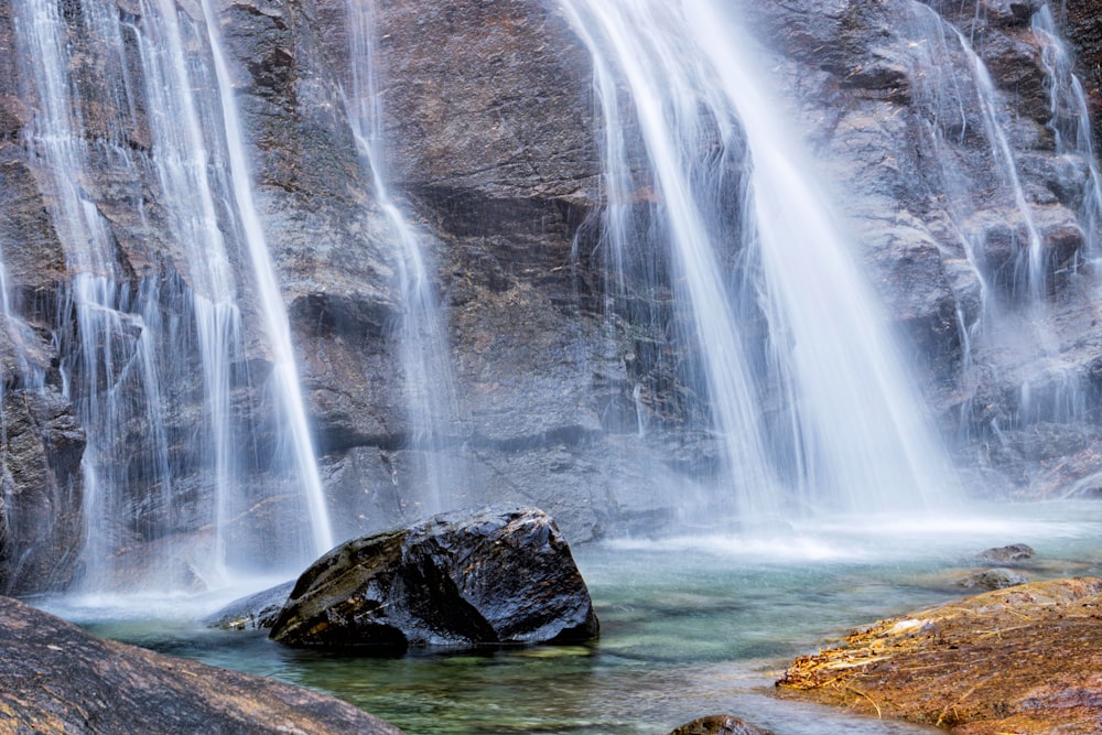 a waterfall with a large rock in the middle of it