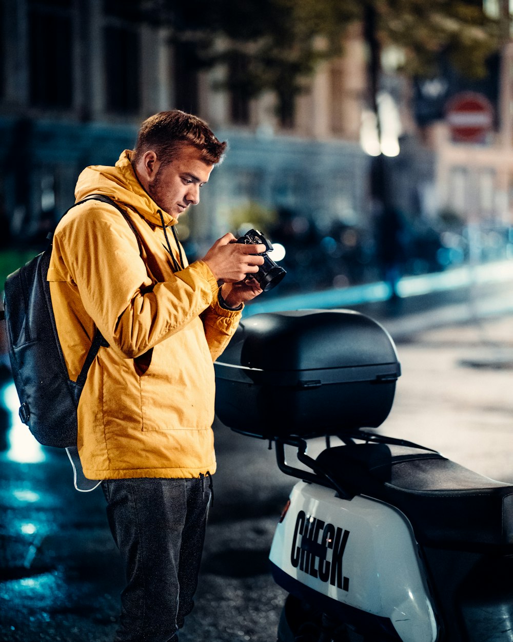 a man standing next to a scooter looking at his cell phone