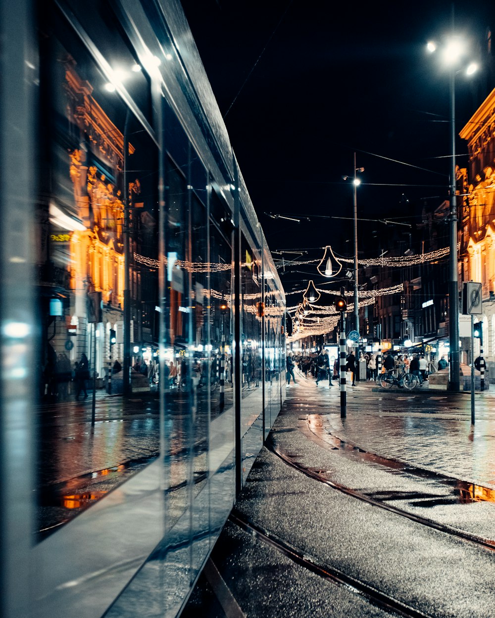 a city street at night with people walking on the sidewalk