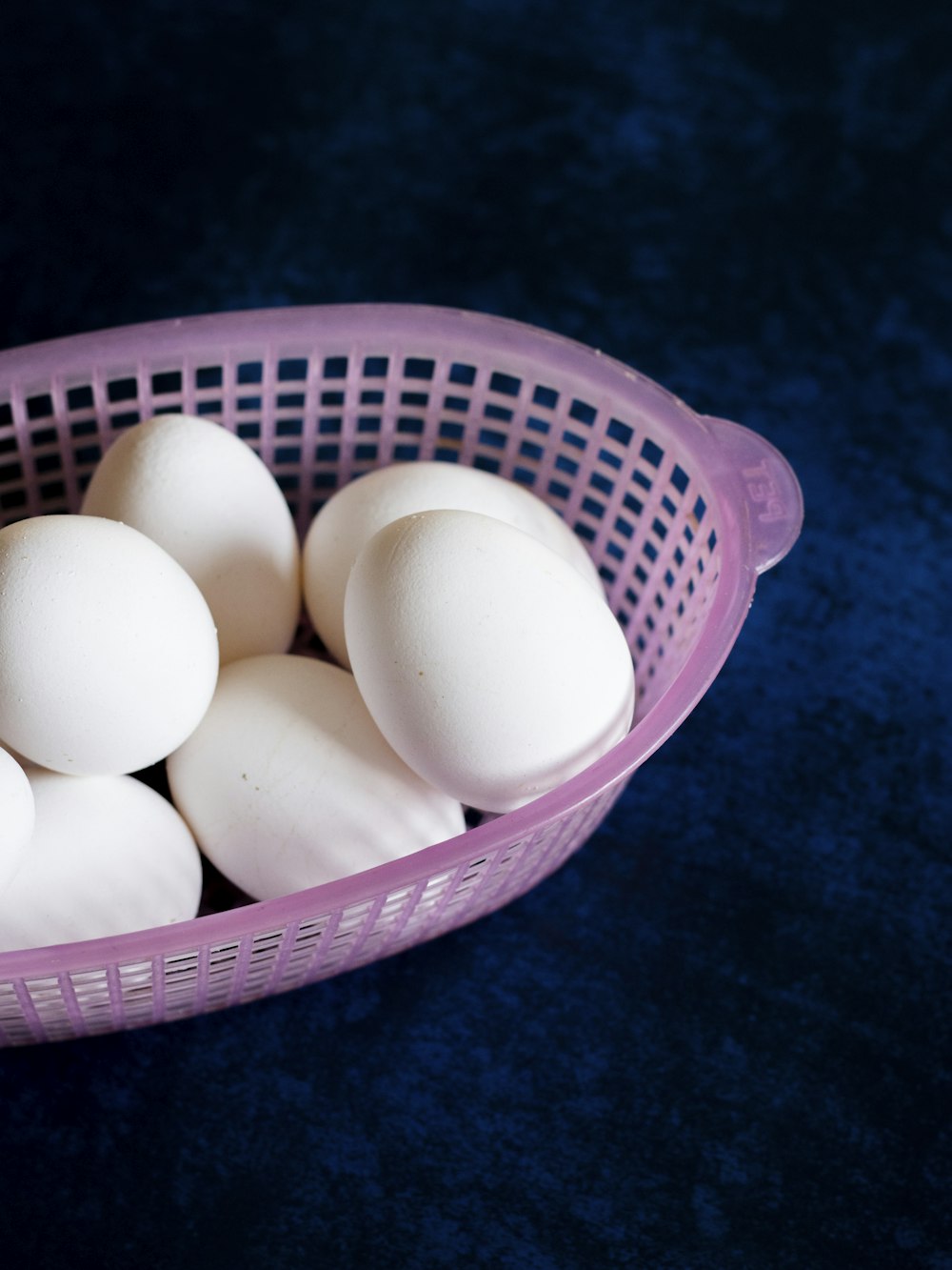 a purple basket filled with white eggs on a blue surface