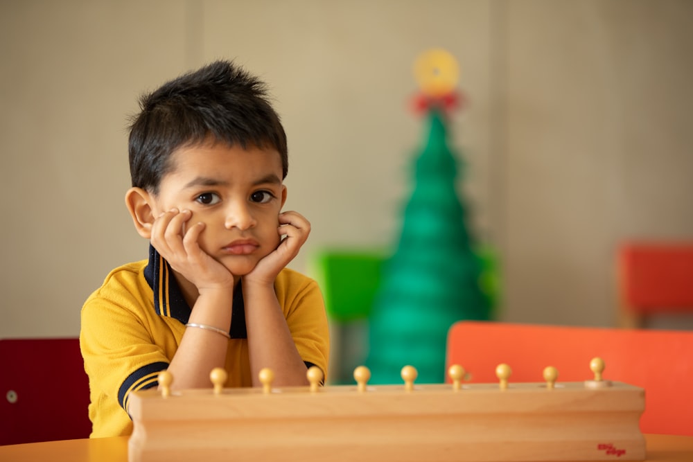 Ein kleiner Junge sitzt an einem Tisch mit einer Partie Schach vor sich