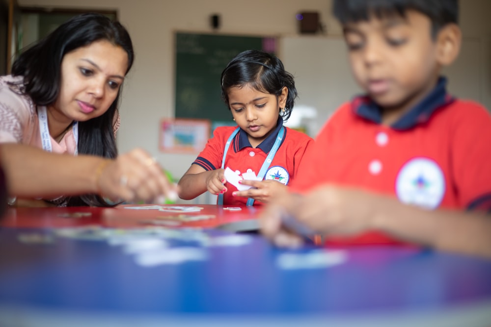 a woman and two children are playing with a puzzle