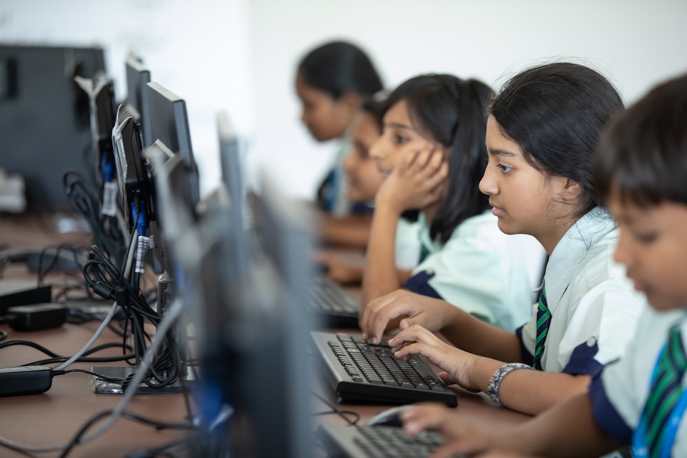 a group of young children sitting at a computer desk