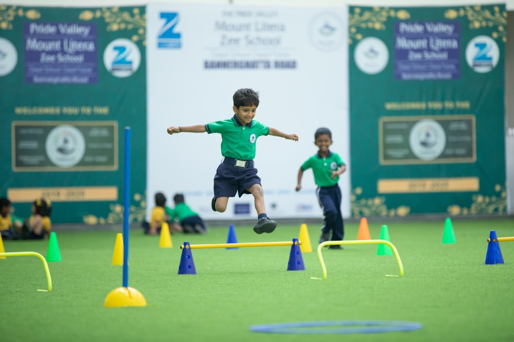 a young boy is jumping over a set of obstacles