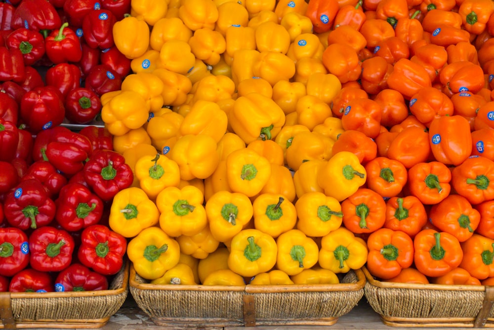 a display of different colored peppers in baskets