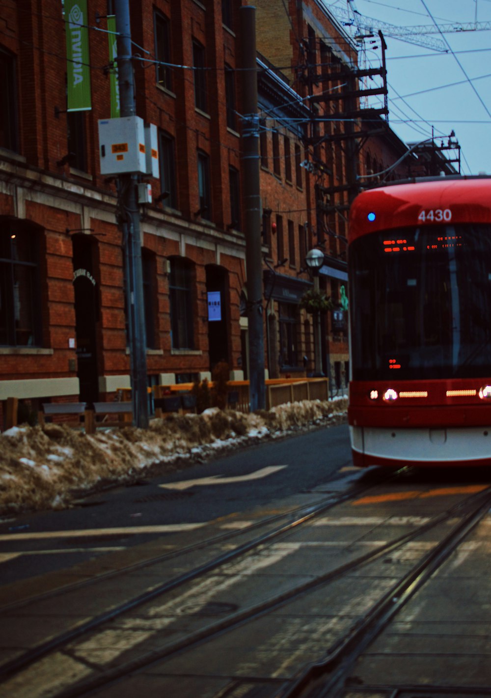 a red and white train traveling down a street next to tall buildings