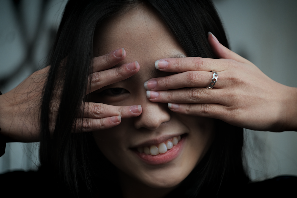 a close up of a person covering their eyes