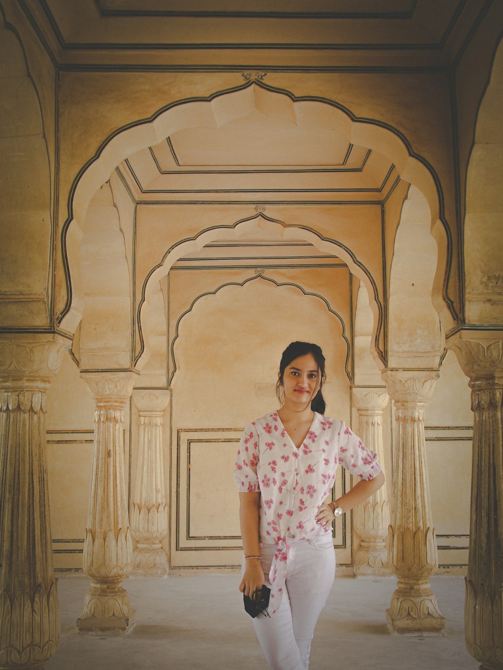 a woman standing in a room with pillars and arches