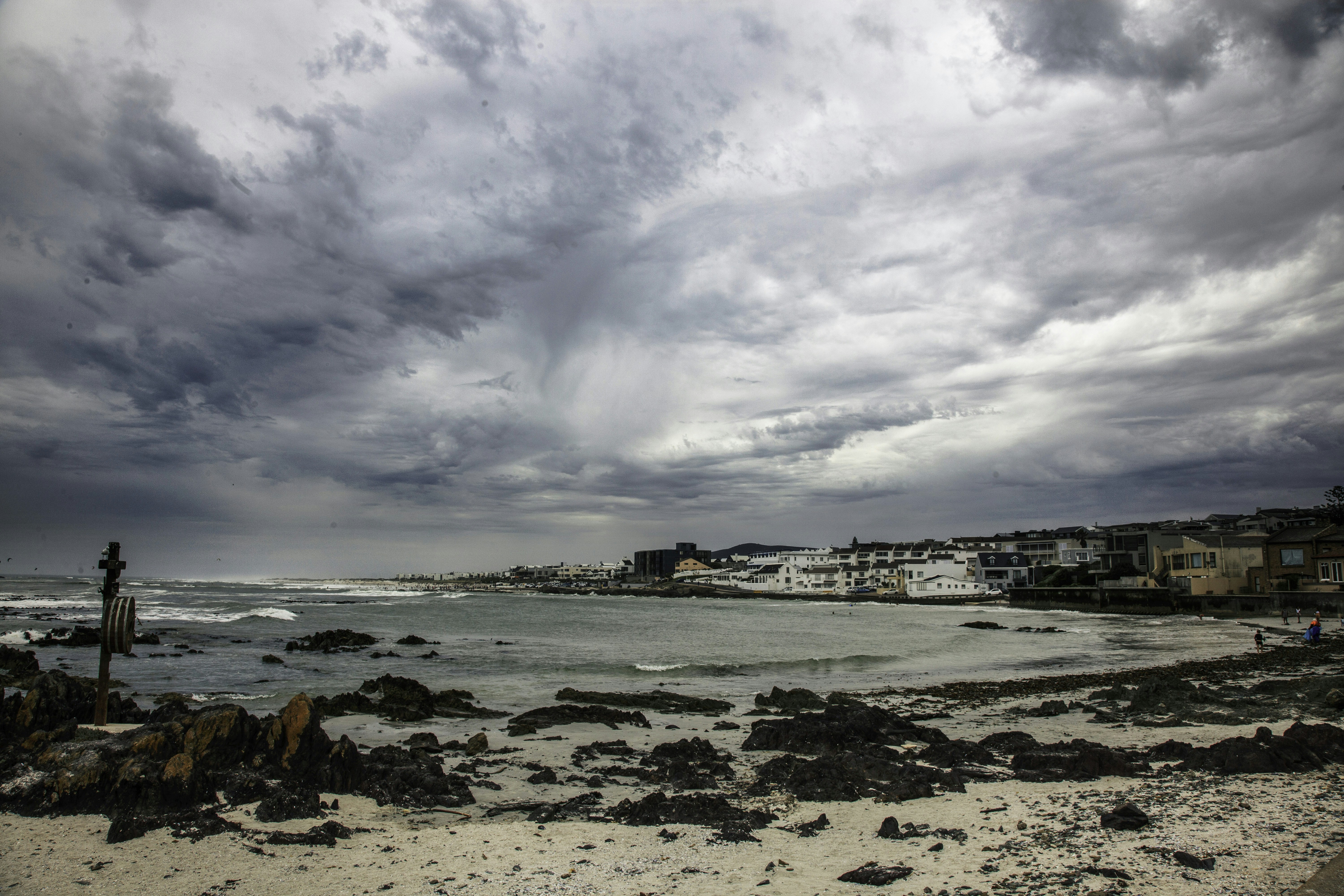 a cloudy day at the beach with houses in the distance