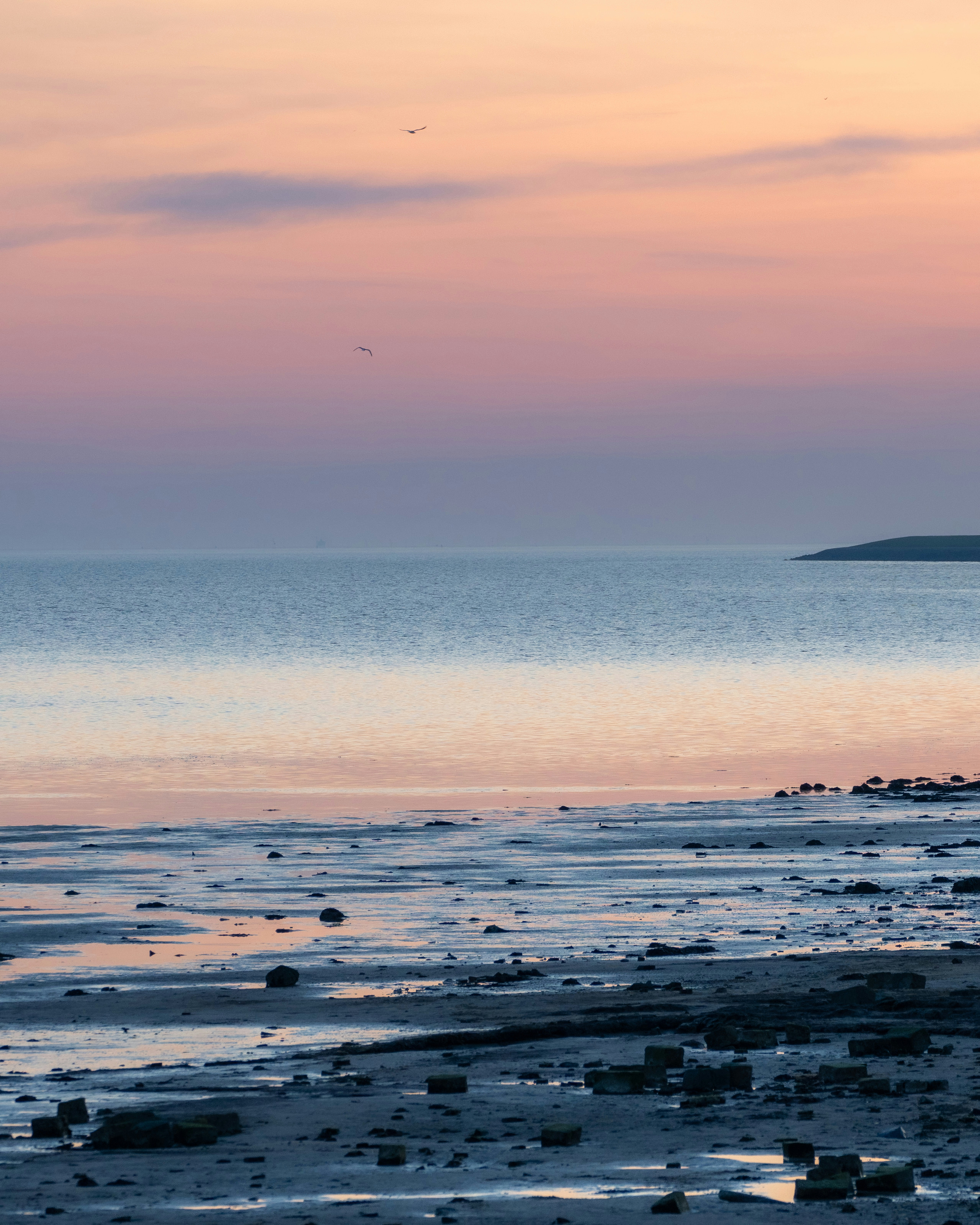 Eine Person, die bei Sonnenuntergang am Strand spazieren geht