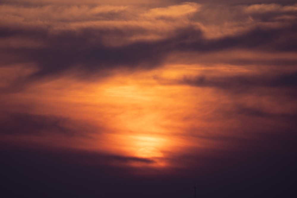 a plane flying in the sky at sunset