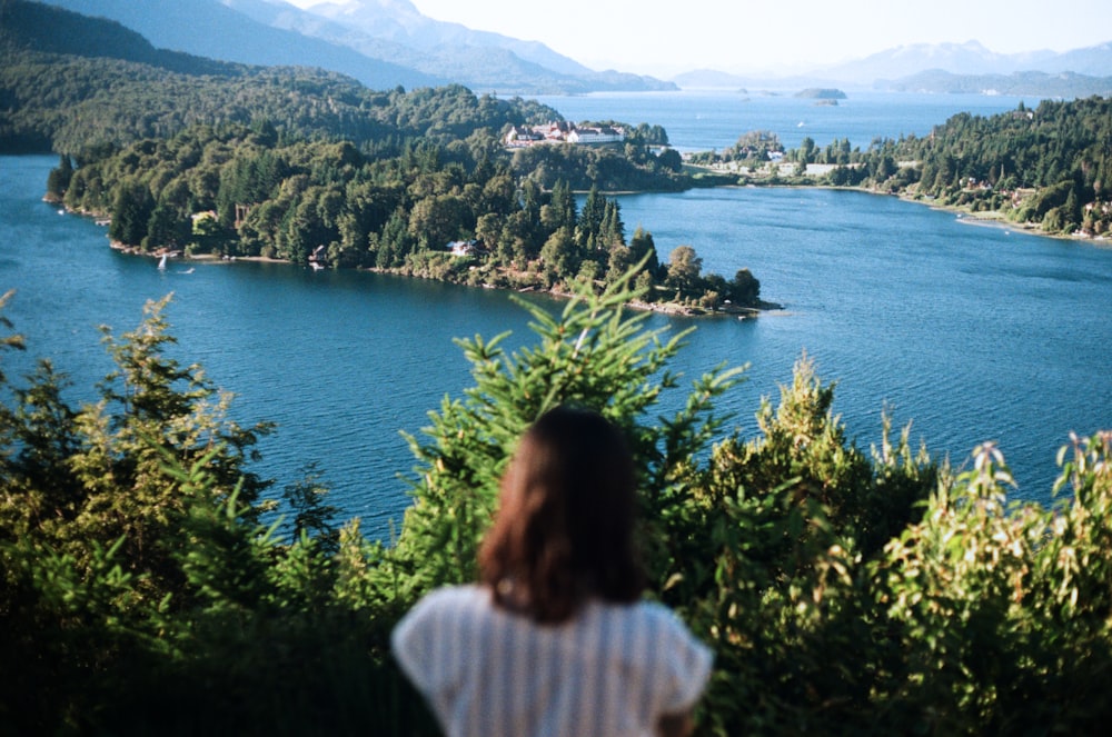 a woman standing on a hill looking at a lake