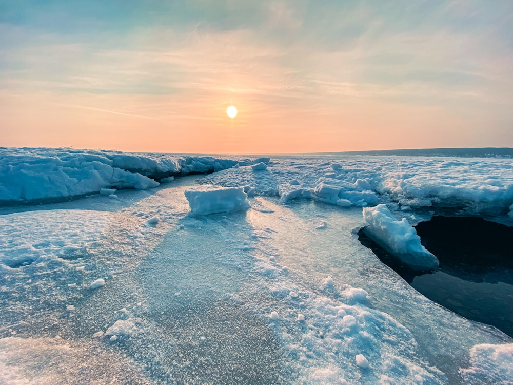 the sun is setting over the ice on the water