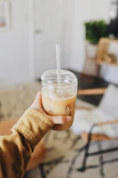 Close-up of a hand holding a twistara tumbler filled with iced coffee, condensation visible