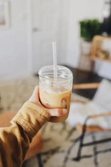 Close-up of a hand holding a twistara tumbler filled with iced coffee, condensation visible
